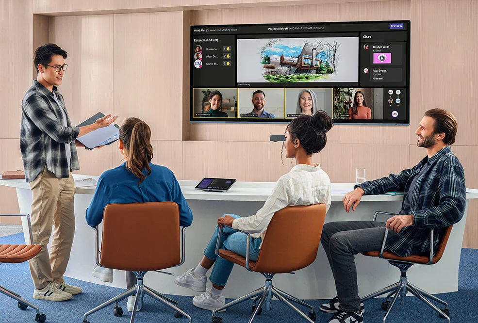 An ultra-wide display running a Microsoft Teams meeting in the Front Row layout, with a team at a curved meeting table